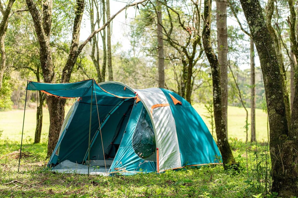 Carpa para 4 personas instalada en un campamento al aire libre, rodeada de árboles.